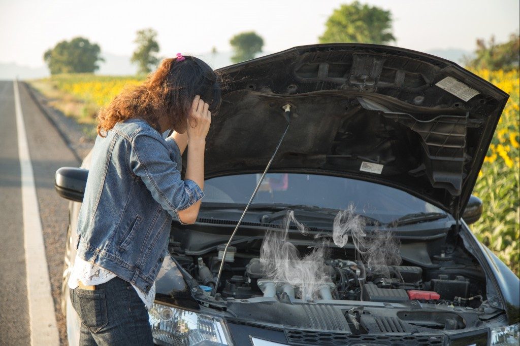 woman checking her broke down car